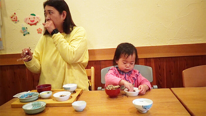 手づかみ食べをする幼児と母親