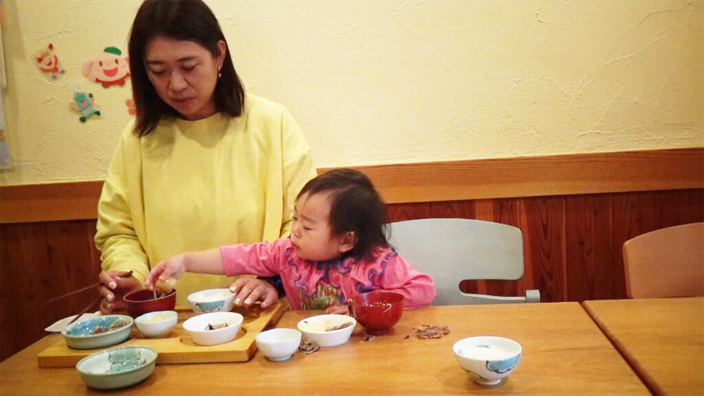 手づかみ食べをする幼児と見守る母親