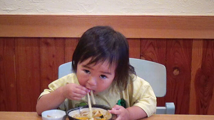 幼児が手づかみでうどんをすする様子