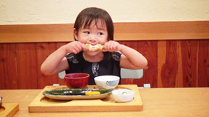 幼児が両手でお肉を掴んで食べてる様子